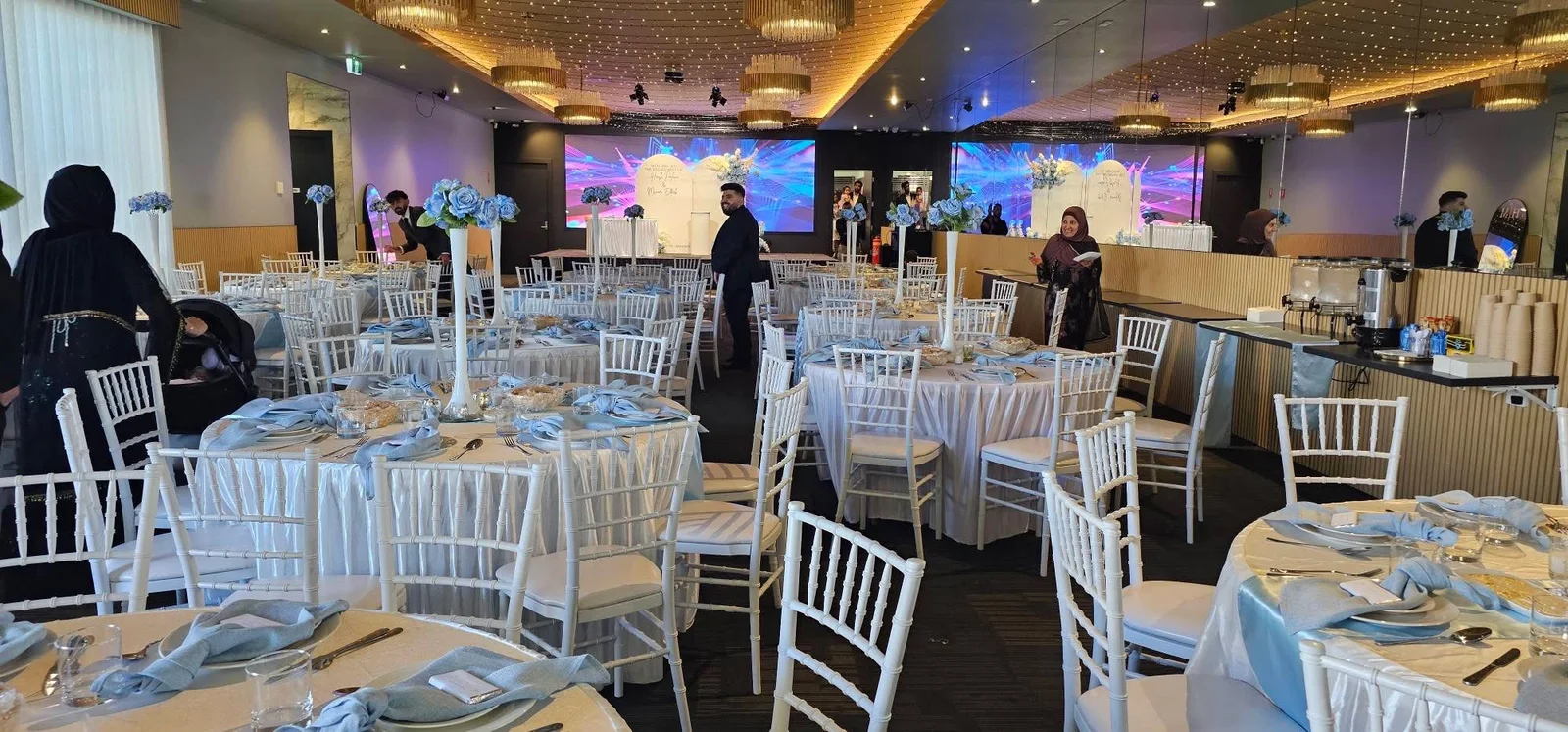 The Vibes Venue arranged with round tables, white chairs and blue styling
