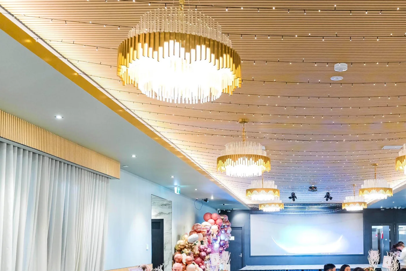 Projector screen, stage lighting and chandeliers inside The Vibes Venue